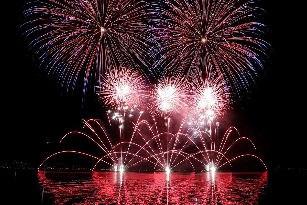 Ein Feuerwerk am Nachthimmel über einem See.